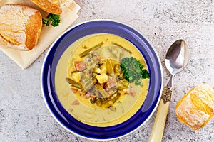 Creamy vegetable soup made from cut green beans, carrot, potato and ham