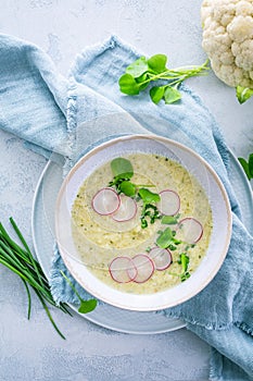 Creamy white cauliflower soup with radish and chives, healthy food with herbs photo