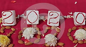 Create 2020 with almonds and flowers on pink background