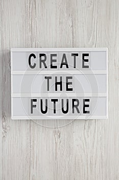 `Create the future` word on modern board on a white wooden background, top view. From above, flat lay, overhead