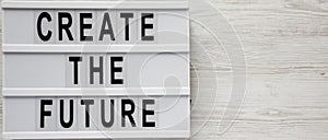 `Create the future` word on modern board on a white wooden background, top view. From above, flat lay, overhead. Copy space