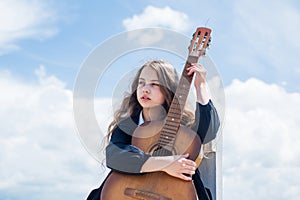 Create new song. small guitar player on sky background. country music style. string musical instrument. play on acoustic