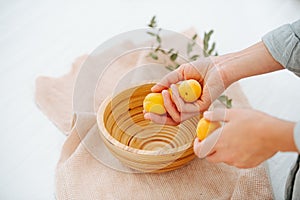 Creating composition, placing fresh ripe apricots in a handmade wooden bowl