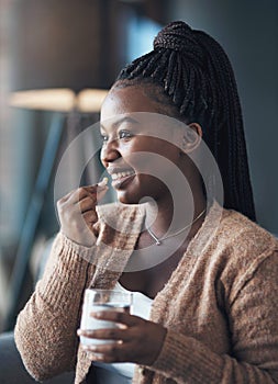 Creating a healthy habit of daily vitamin intake. an attractive young woman sitting alone and taking her medication with