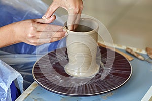 Creating jar or vase of clay. Woman hands, potter`s wheel photo