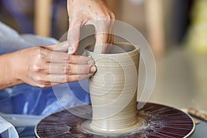 Creating jar or vase of clay. Woman hands, potter`s wheel photo