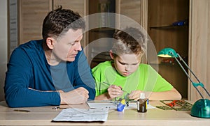 Creating the model plane. Happy son and his father are making aircraft model. Hobby and family concept.