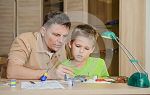 Creating the model plane. Happy son and his father are making aircraft model. Hobby and family concept.