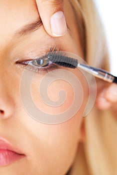 Creating volume and length. Cropped view of a young woman having mascara applied to her eyelashes.