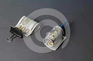 Creative abstract background with one hundred dollar bill clamped in Stationery metal binder clip and clothespin on gray