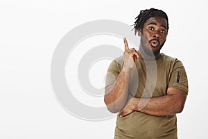 Creative african-american bearded guy in military t-shirt, raising index finger in eureka gesture, having great plan or