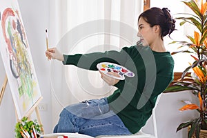Creative of art concept, Young asian woman hold paintbrush in front of canvas to measure proportion