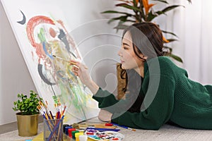 Creative of art concept, Young asian woman lying on the floor and using paintbrush to painting art