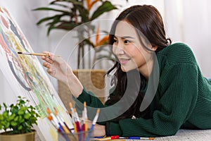 Creative of art concept, Young asian woman lying on the floor and using paintbrush to painting art