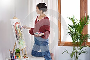 Creative of art concept, Young asian woman use paintbrush and color palette to painting on canvas