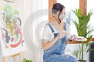 Creative of art concept, Young asian woman use paintbrush to dip in palette for painting on canvas