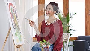 Creative of art concept, Young asian woman using paintbrush to drawing on canvas in the art studio