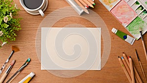 Creative art workspace, blank paper sheet for your project surrounded by painting tools