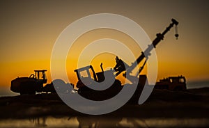 Abstract Industrial background with construction crane silhouette over amazing sunset sky. Mobile crane against the evening sky.