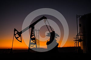 Creative artwork decoration. Oil pump and oil refining factory at sunset. Energy industrial concept. Selective focus