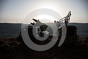 Creative artwork decoration. Silhouette of mobile air defence truck with radar antenna during sunset. Satellite dishes or radio