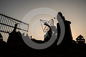 Creative artwork decoration. Silhouette of mobile air defence truck with radar antenna during sunset. Satellite dishes or radio