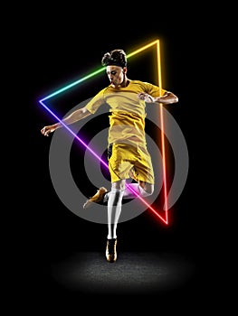 Creative artwork of prfessional male football player in motion over neon geometric element isolated over black