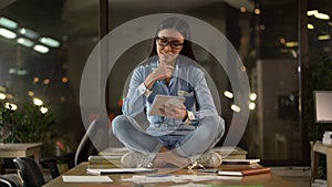 Creative Asian woman sitting on office table, thinking over startup ideas