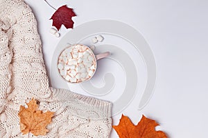 Creative autumn composition with warm knitted sweater, yllow leaves and cocoa with marshmallows