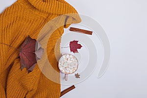 Creative autumn composition with warm knitted sweater, yllow leaves and cocoa with marshmllows