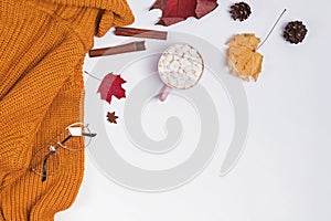 Creative autumn composition with warm knitted sweater, yllow leaves and cocoa with marshmllows
