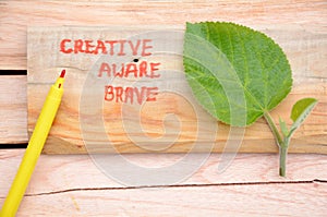 Creative ,aware,brave,write in the wooden mental health awareness concept with green blue berry leaf on the wooden background