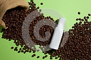 Creative background for advertising with white empty bottle displayed on coffee beans and green background. Top view. Coffee