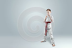 Creative background a child in a white kimono in a fighting stance, on a light background
