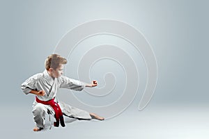 Creative background a child in a white kimono in a fighting stance, on a light background The concept of martial arts