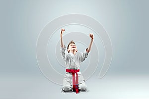 Creative background, a child in a white kimono rejoices victory, on a light backgroundThe concept of martial arts karate