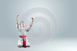 Creative background, a child in a white kimono rejoices victory, on a light backgroundThe concept of martial arts karate