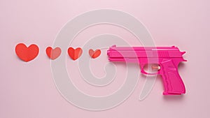 Creative background made with Pink gun and red paper hearts. Minimal love concept