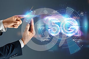 Creative background, a man`s hand holds a phone with a 5G hologram on the background of the city. 5G network concept, high speed