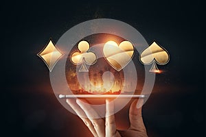 Creative background, online casino, in a man`s hand a smartphone with playing cards, roulette and chips, black-gold background.