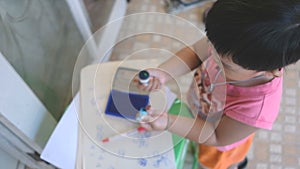 Creative boy using stamper with blue ink and stamp on paper as artwork from high angle view