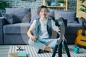 Creative boy vlogger recording video for online vlog speaking on floor at home photo