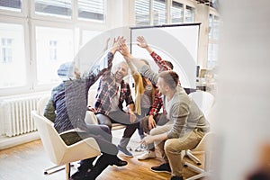 Creative business people giving high-five in meeting room