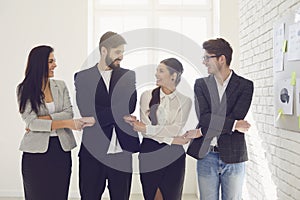 Creative business people team holding hands while standing indoors.