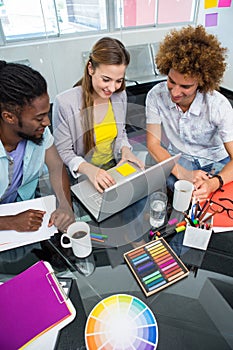 Creative business people using laptop at desk