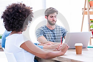 Creative business people using laptop in meeting