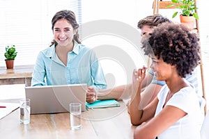 Creative business people using laptop in meeting