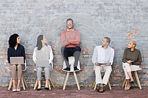 Creative business people, waiting room and man standing out against a brick wall for interview, meeting or opportunity