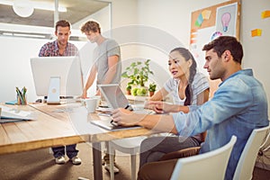 Creative business team gathered around laptops photo