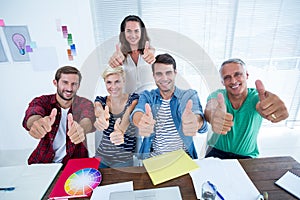 Creative business team gesturing thumbs up in meeting